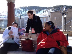 Maggie Woodward, Leah Railey, and Dillon Ward studying the Sundance program while waiting for the Theater Loop shuttle at the Main Street depot in Park City, Utah.